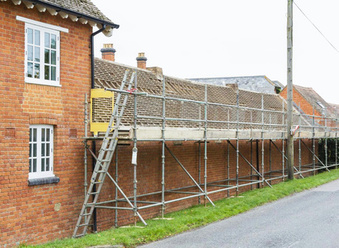 Side view of a house with scaffolding and a ladder undergoing roof refurbishment work