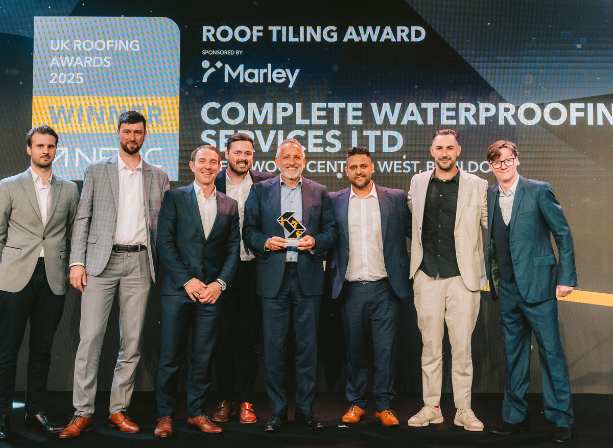 Complete Waterproofing Services Ltd team on stage at UK Roofing Awards with Ed Byrne